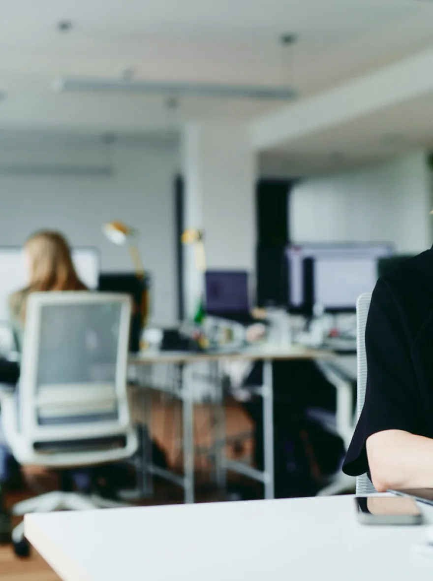 Helles Büro mit Arbeitsplätzen und Kollegin am Bildschirm