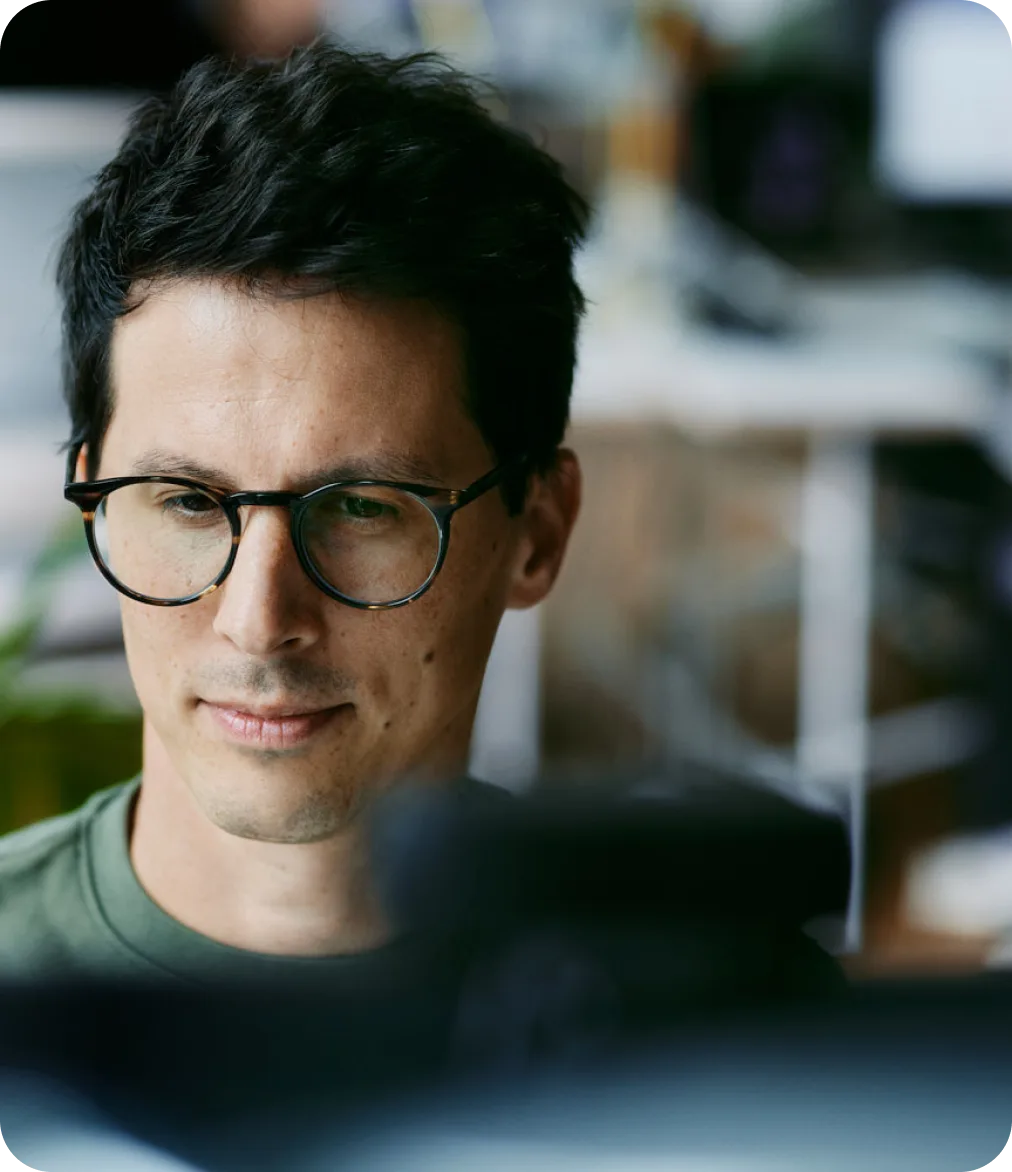 Konzentrierter Kollege mit Brille bei der Arbeit am Bildschirm